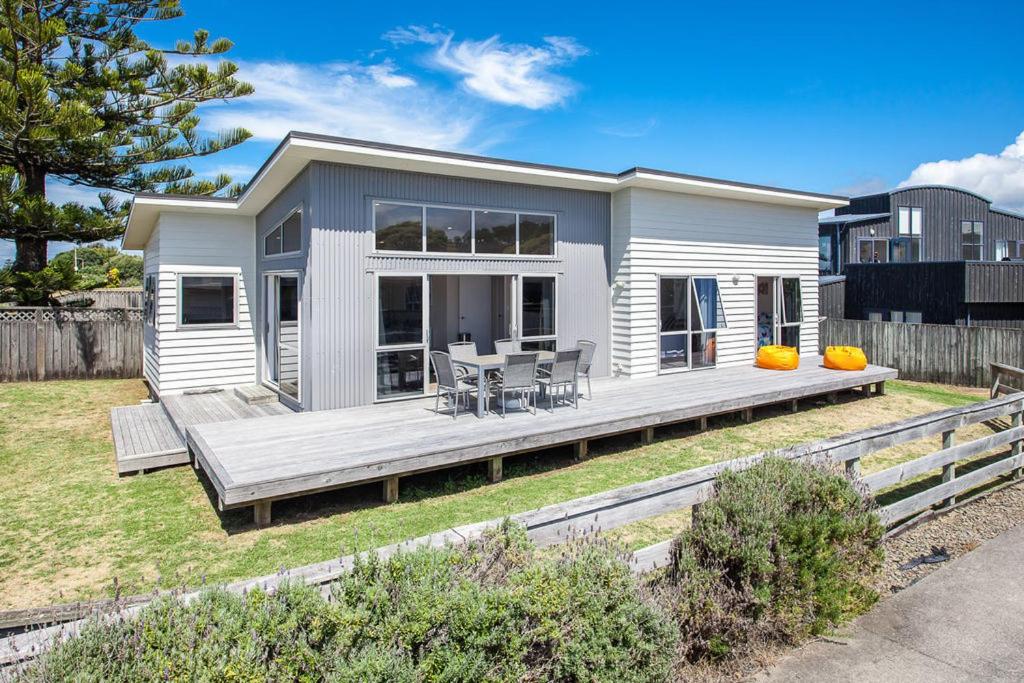 a small white house with a wooden deck at Beach Retreat - Ohope Holiday Home in Ohope Beach