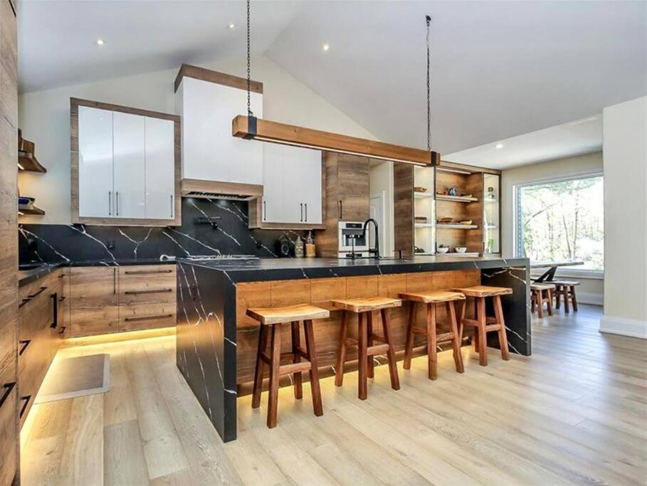 a large kitchen with wooden counters and wooden stools at Chic & luxurious villa with outdoor sauna in Wymbolwood Beach