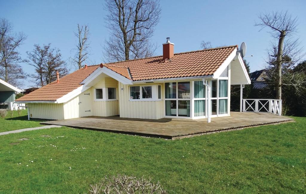 ein kleines weißes Haus mit einer Holzterrasse in der Unterkunft Strandpark 22 in Schönhagen