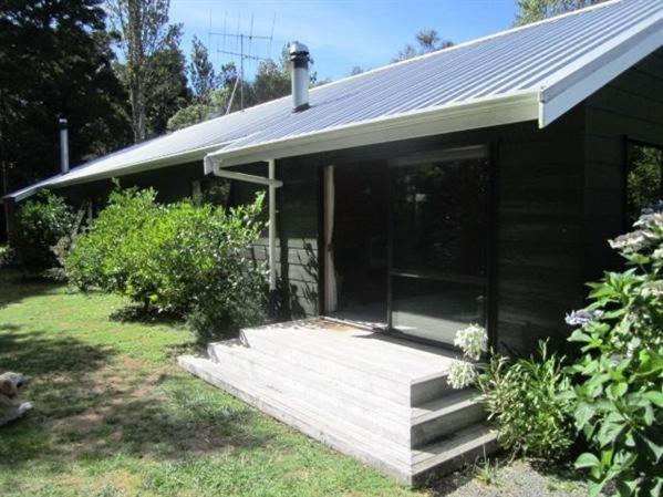 uma pequena casa preta com um alpendre e um quintal em Puka Lodge Front dwelling - Pukawa Bay Home em Kuratau
