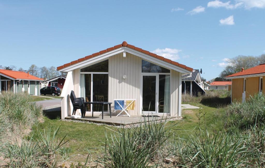 ein kleines weißes Cottage mit einem Tisch im Hof in der Unterkunft Dnenpark 2 - Dorf 4 in Travemünde