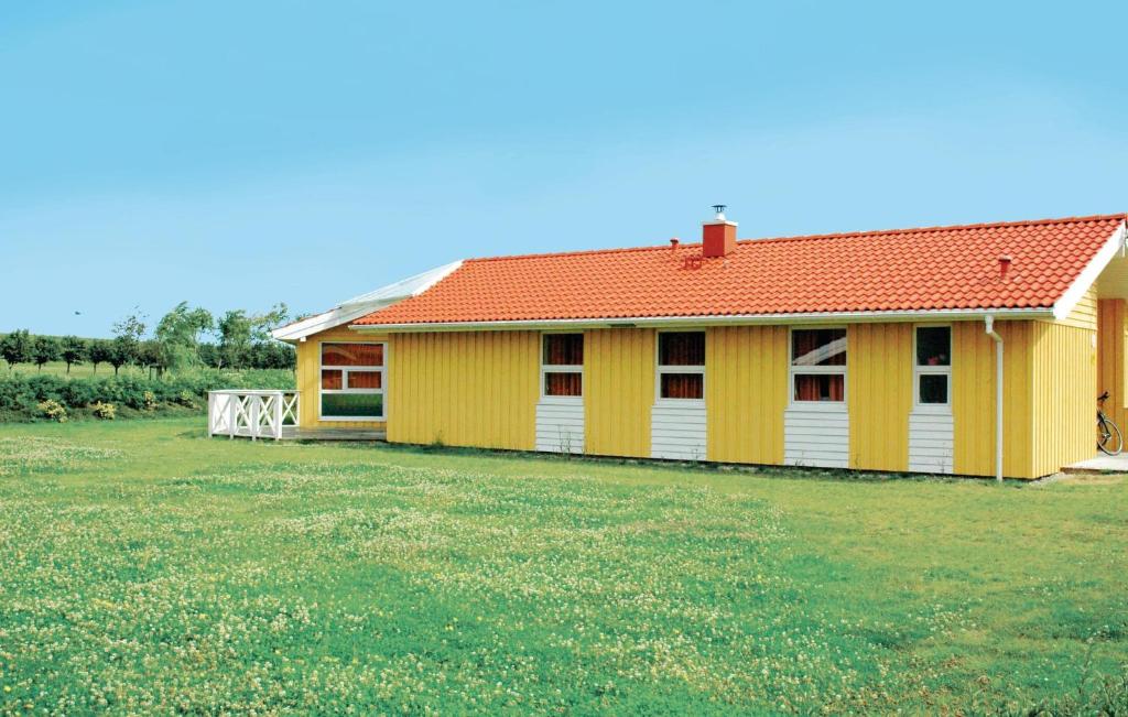 ein gelbes Haus mit rotem Dach auf einem Feld in der Unterkunft Friedrichskoog-strandpark 10 in Friedrichskoog