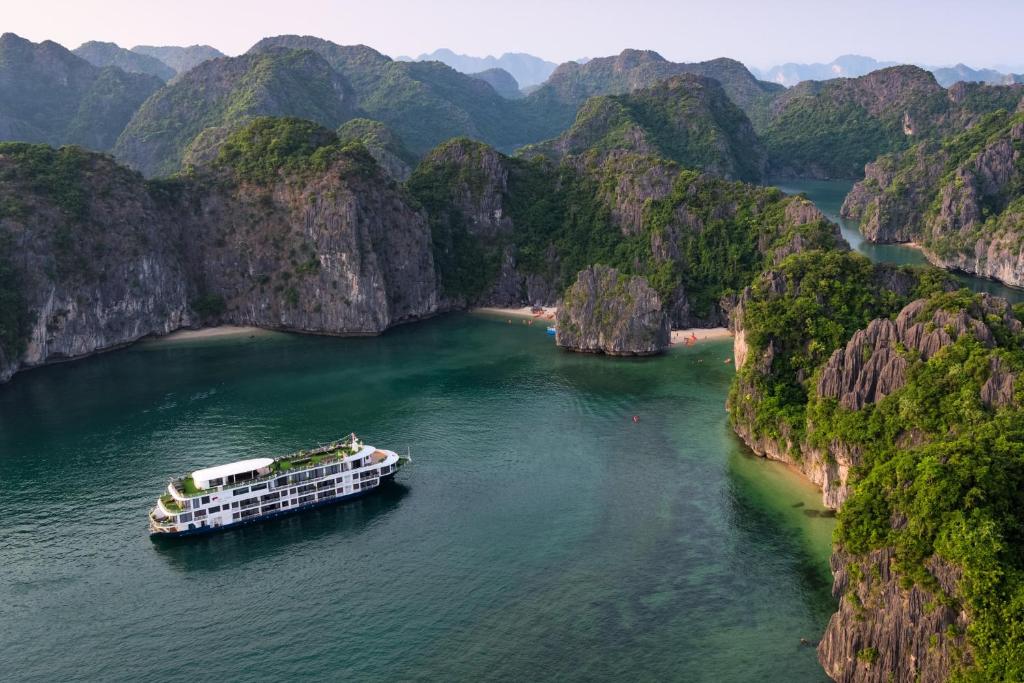 a boat on a river in a mountain region at Mon Cheri Cruises in Ha Long