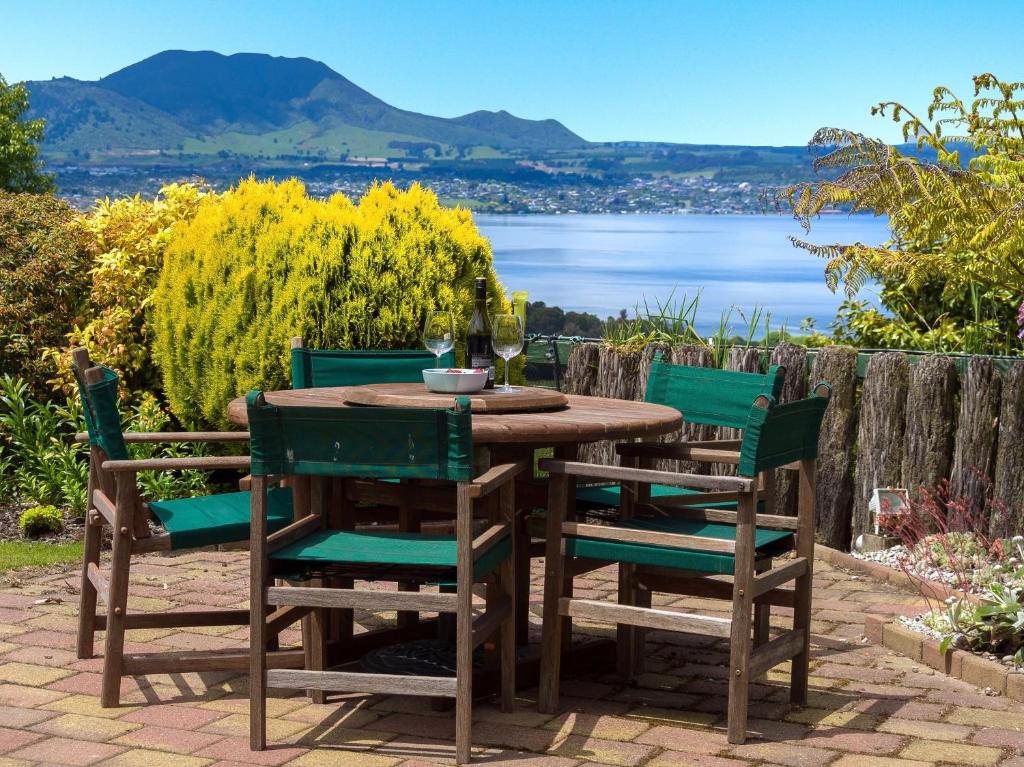 a wooden table and chairs with a view of the water at Laketop Retreat - Acacia Bay Holiday Home in Taupo