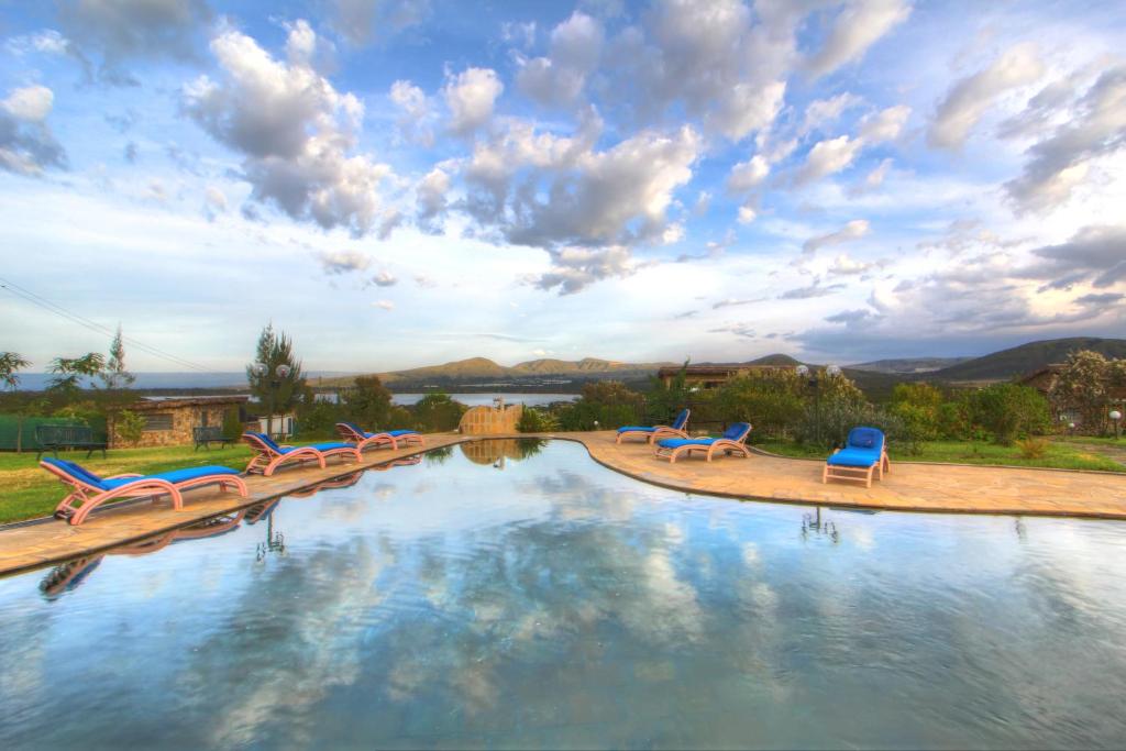 una gran piscina con sillas azules y un cielo nublado en Naivasha Kongoni Lodge - Lakefront Getaway en Naivasha
