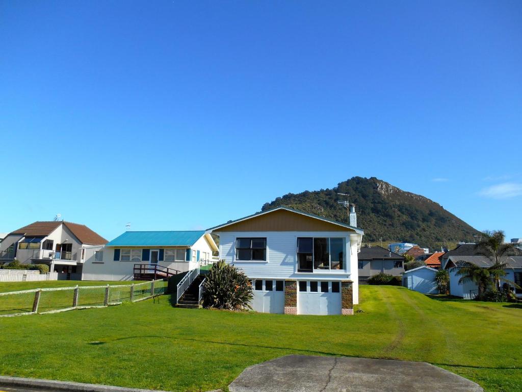 a house on a lawn with a mountain in the background at Bobs Bach - Mt Maunganui Bach in Mount Maunganui