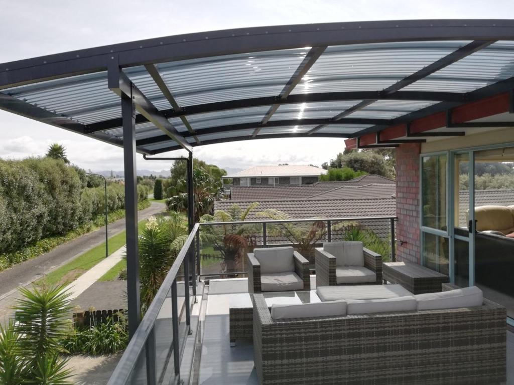 awning over a patio with couches on a house at Tuis Nest - Bowentown Holiday Home in Waihi Beach