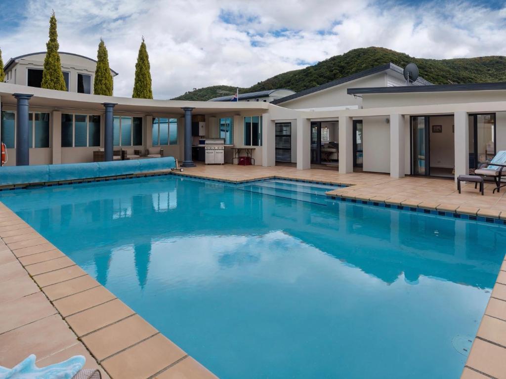 a swimming pool in front of a house at Poolside Retreat - Picton Holiday House Waikawa in Picton