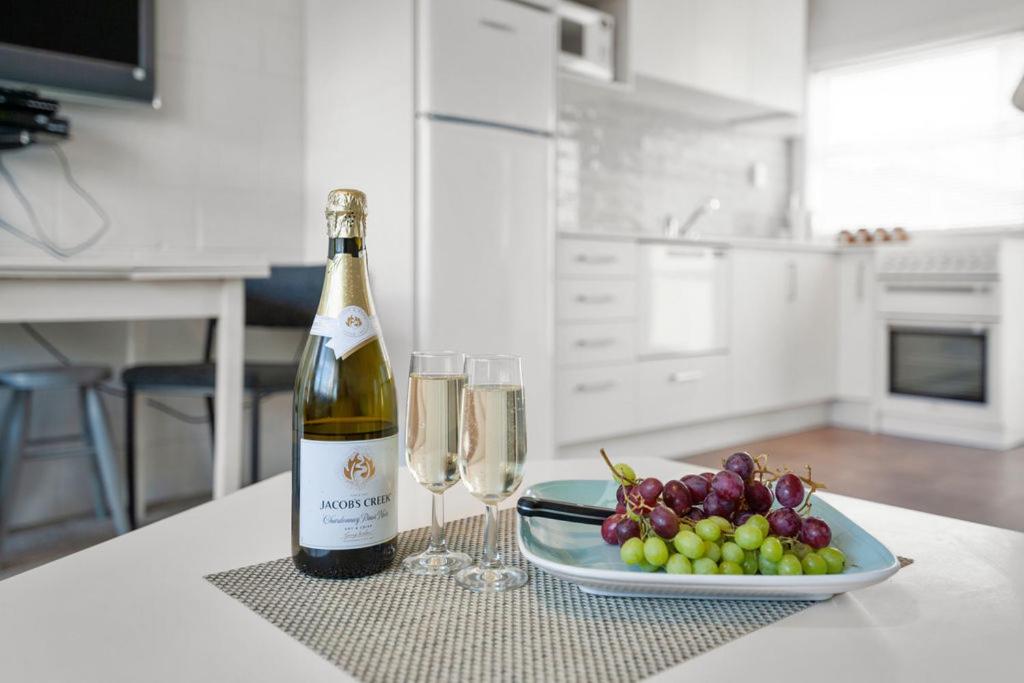 une bouteille de vin et une assiette de raisins sur une table dans l'établissement Central Stay - Taupo Flat, à Taupo