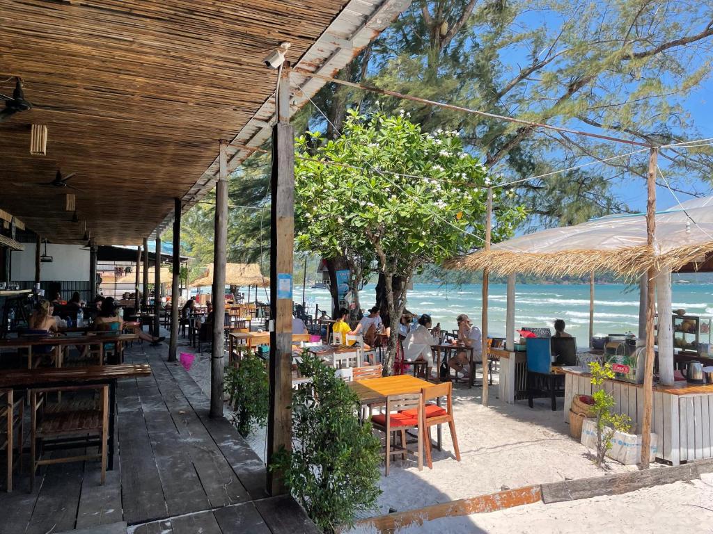 a patio area with tables, chairs and umbrellas at Onederz Koh Rong Sanloem in Koh Rong Sanloem
