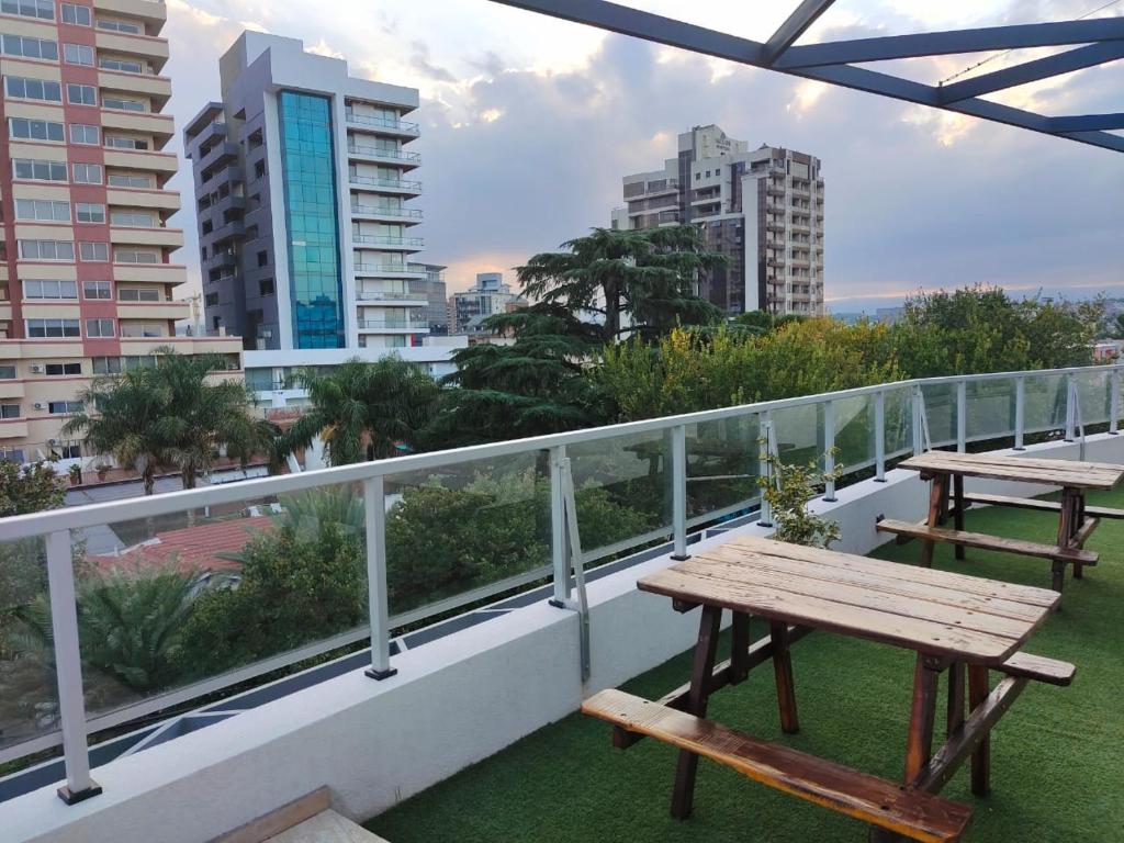 balkon z dwoma stołami piknikowymi i widokiem na miasto w obiekcie Apartamento Carlos Paz w mieście Villa Carlos Paz
