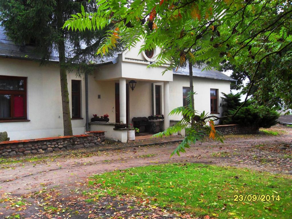 Una casa blanca con un árbol delante. en Kasztelania Pod Lipami, en Zakroczym