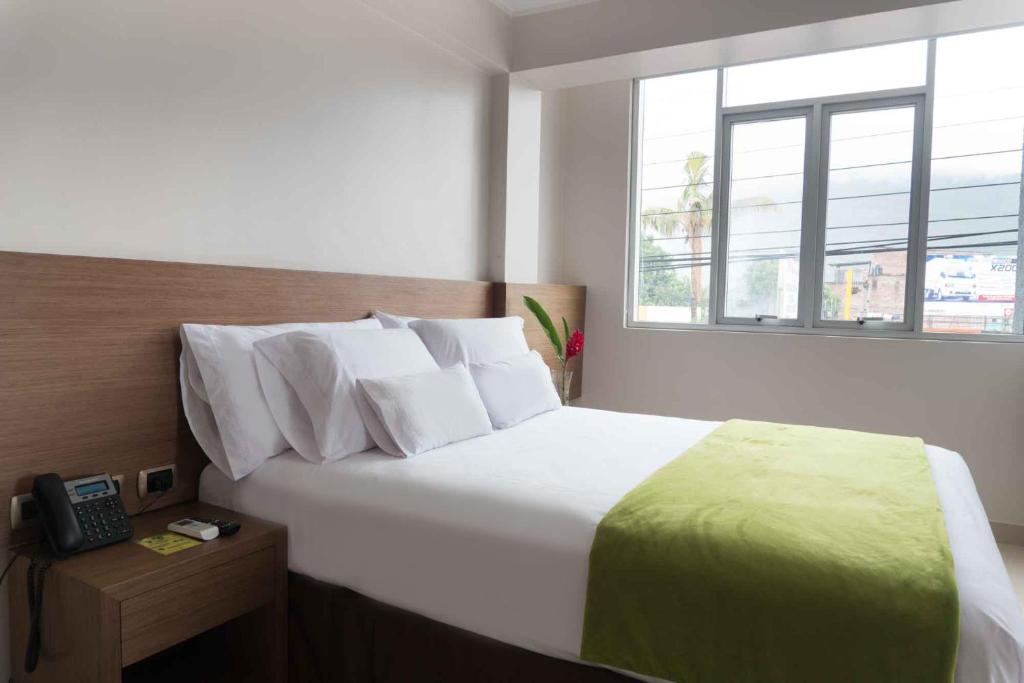 a bedroom with a bed with a telephone and a window at Hotel Monte Cafeto INN in Pichanaki