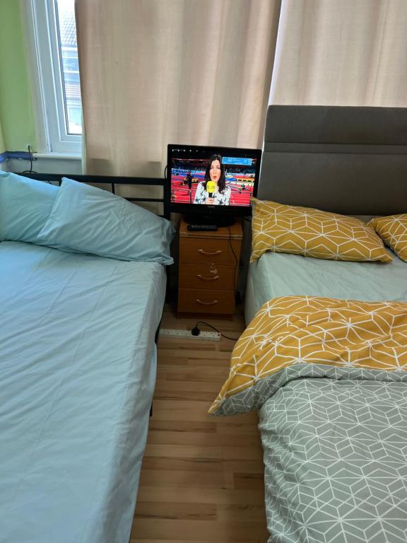 a bedroom with two beds and a flat screen tv at Luxury suite in Summerseat