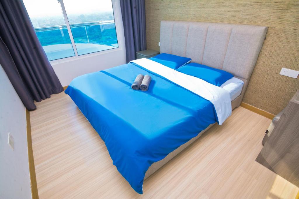 Cama azul en habitación con ventana grande en Cardamom The Wave&Atlantis Residence Melaka Town, en Melaka