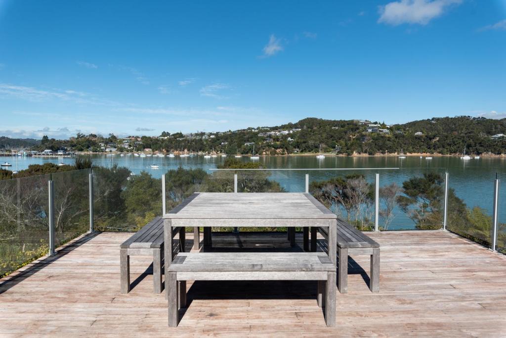 a picnic table on a deck with a view of the water at The Tide Watcher - Okiato Holiday Home in Opua