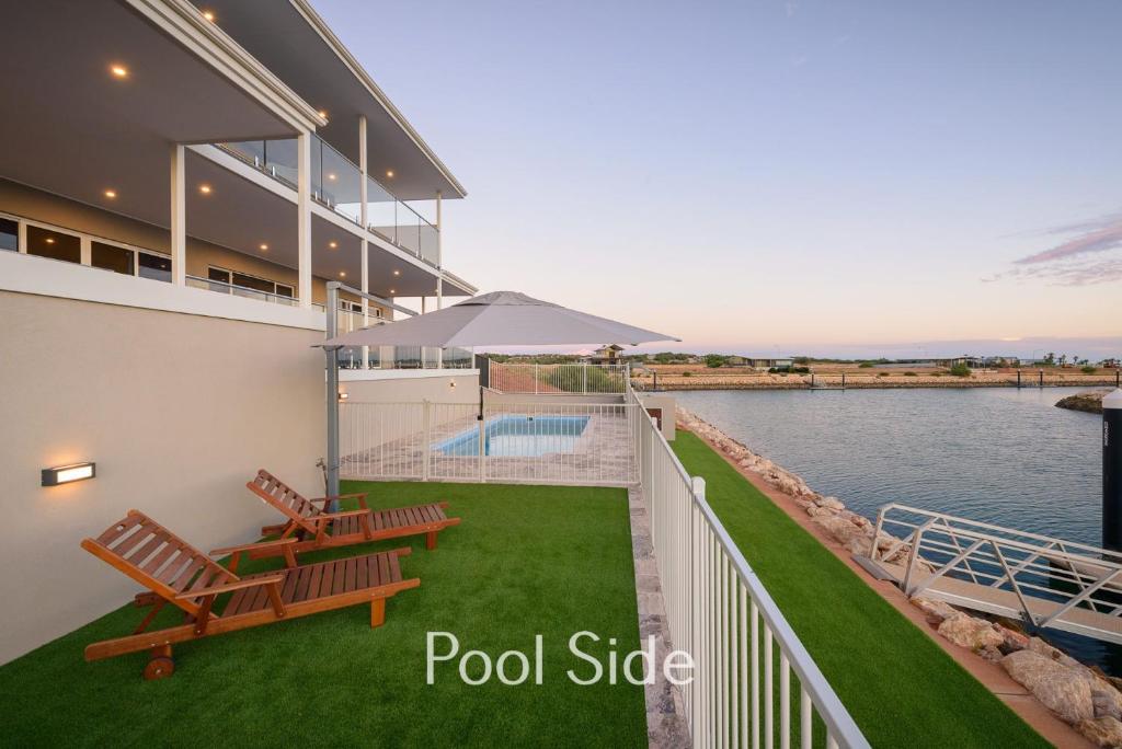 a view of a house with a pool and benches at 32 Corella Court in Exmouth