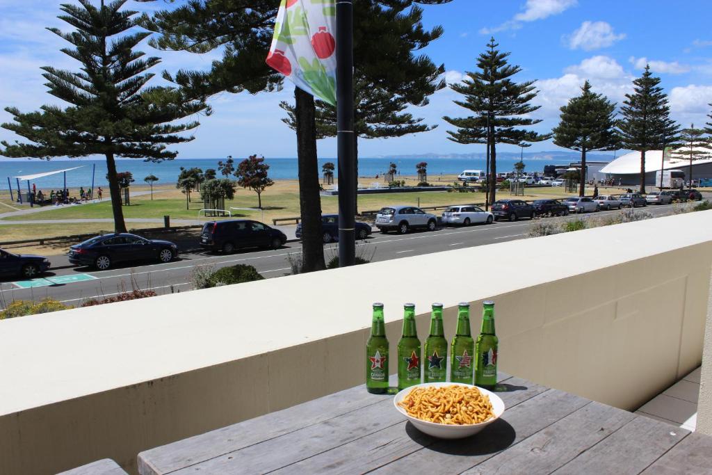 a table with three bottles of wine and a bowl of popcorn at Marine Haven - Napier Holiday Home in Napier