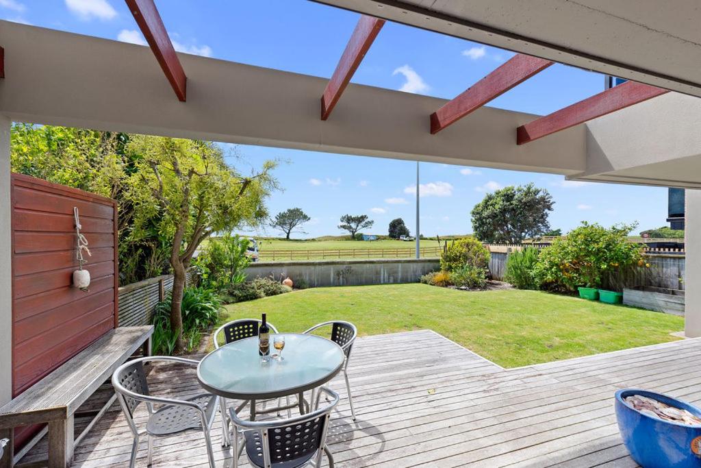 a patio with a table and chairs on a deck at The Sandcastle - Papamoa Holiday Apartment in Papamoa