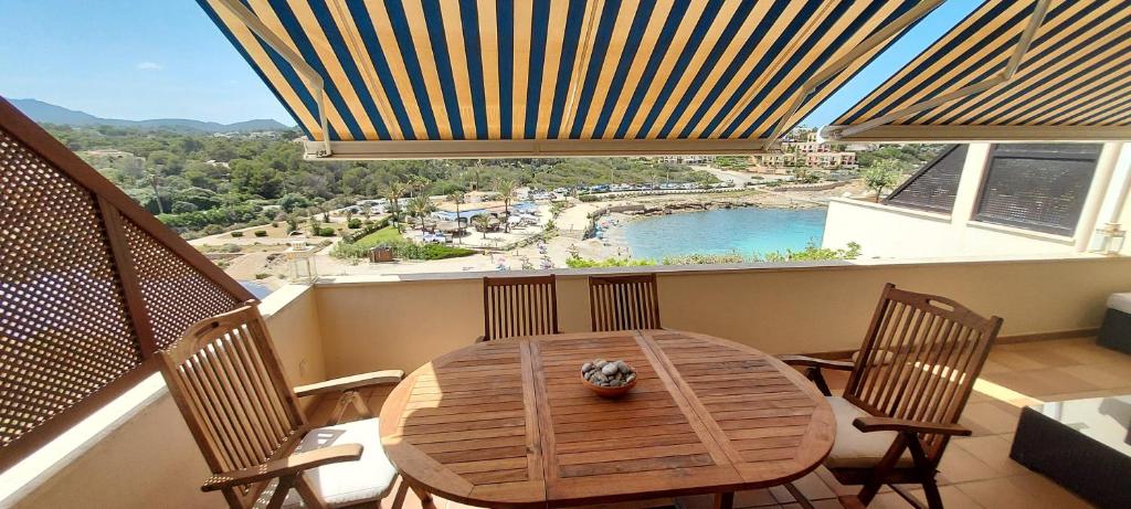 una mesa de madera y sillas en un balcón con vistas en Beach view apartment of 87 m2, big terrace, en Cala Murada