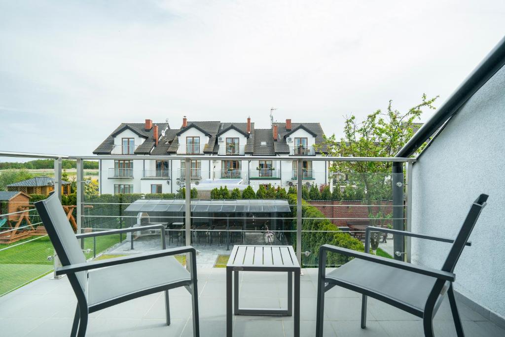a balcony with two chairs and a table and a building at Villa Luka in Łeba
