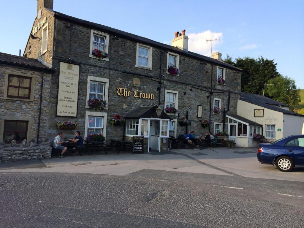 un viejo edificio de piedra con gente sentada fuera de él en The Crown Hotel, en Horton in Ribblesdale