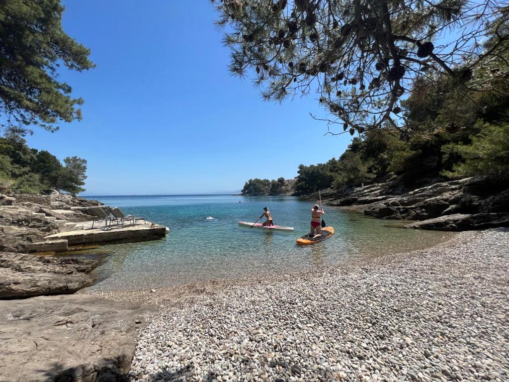 two people on kayaks in the water on a rocky beach at Apartman MaRiTo in Selca
