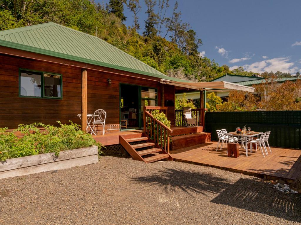 een huis met een houten terras met een tafel en stoelen bij Cedar Cottage - Tairua Holiday Home in Tairua