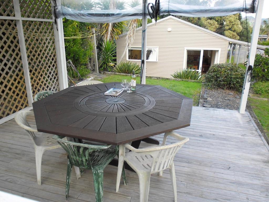 a wooden table and chairs on a wooden deck at Ocean Beach Honey - Tairua Holiday Home in Tairua