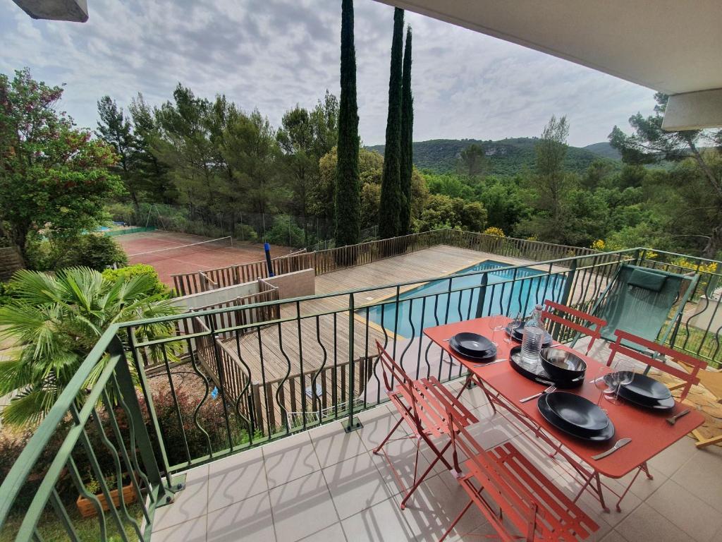 a balcony with a table and chairs and a tennis court at T3 Le Lou-Piscine & Parking - 5min des thermes in Gréoux-les-Bains