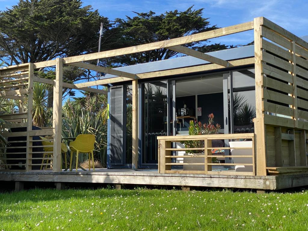a wooden house with a deck and a lawn at Ross Beach TOP10 Holiday Park in Ross