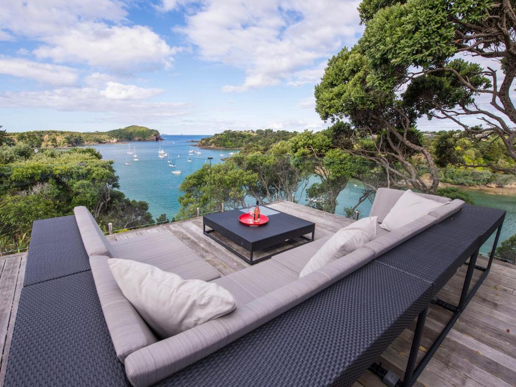 a couch on a deck with a view of the water at Moonlit Knights - Tutukaka Holiday House in Tutukaka