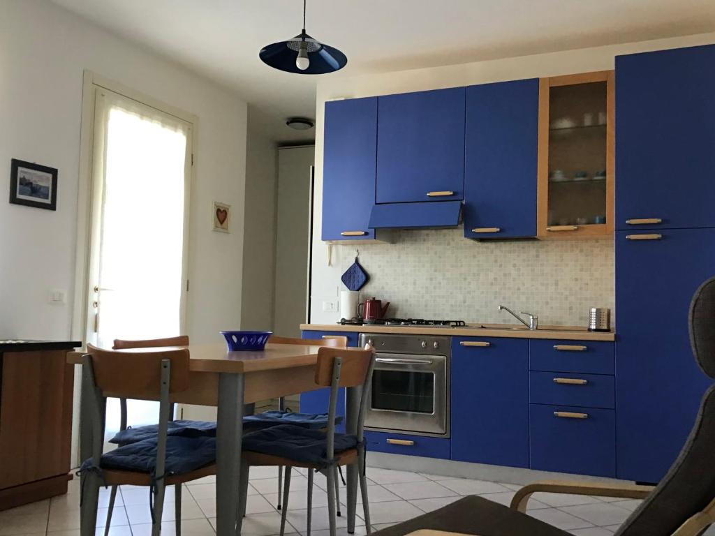 CASA EZZELINA في Romano D'Ezzelino: مطبخ مع دواليب زرقاء وطاولة وكراسي