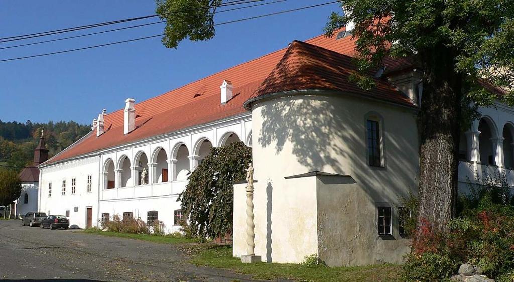 un bâtiment blanc avec un toit rouge à côté d'une rue dans l'établissement Zámek Mokrosuky, à Mokrosuky