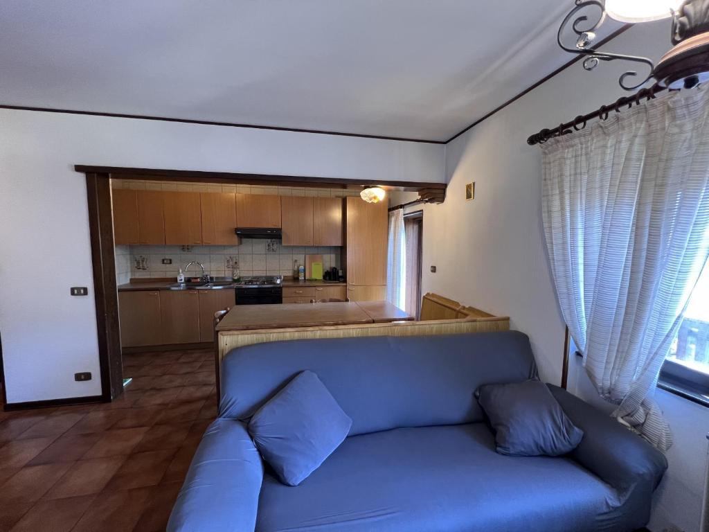 sala de estar con sofá azul y cocina en 050 Trilocale in centro, Pinzolo, en Pinzolo