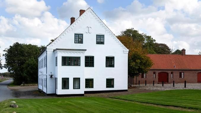 a large white house sitting on top of a lush green field at Skærum Mølle in Vemb