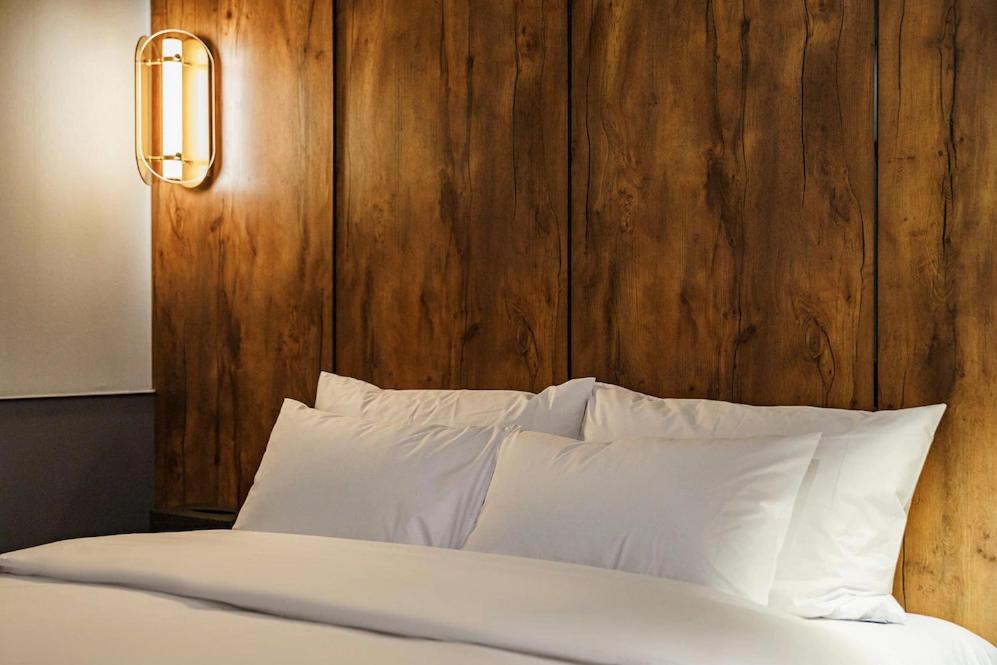 uma cama com almofadas brancas e uma cabeceira em madeira em Brown-Dot Hotel Geomdan em Incheon