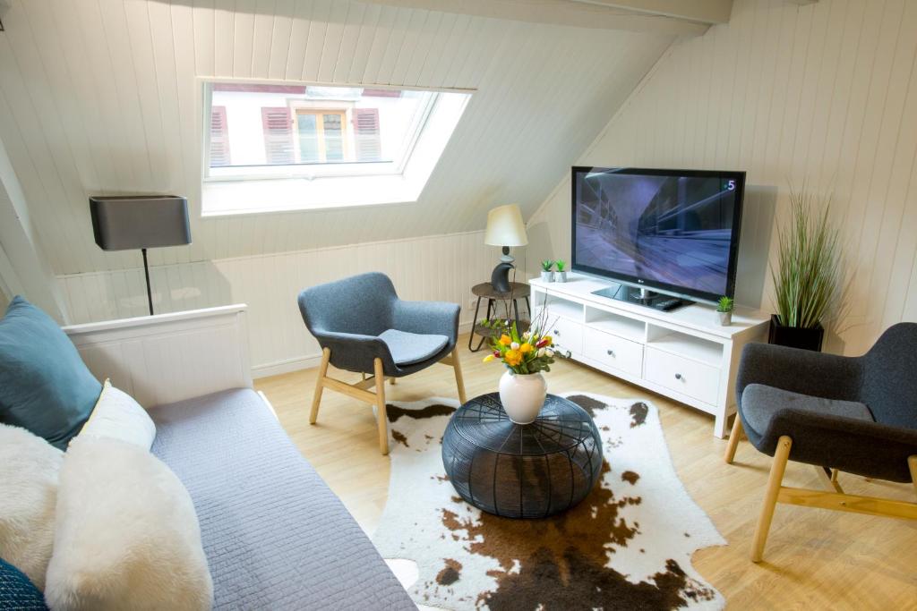 un salon avec un canapé et une télévision dans l'établissement Appartement Les Tournesols avec Climatisation, à Kaysersberg