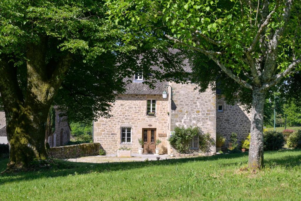 una casa de piedra con árboles delante de ella en Domaine du Vidal en Camps