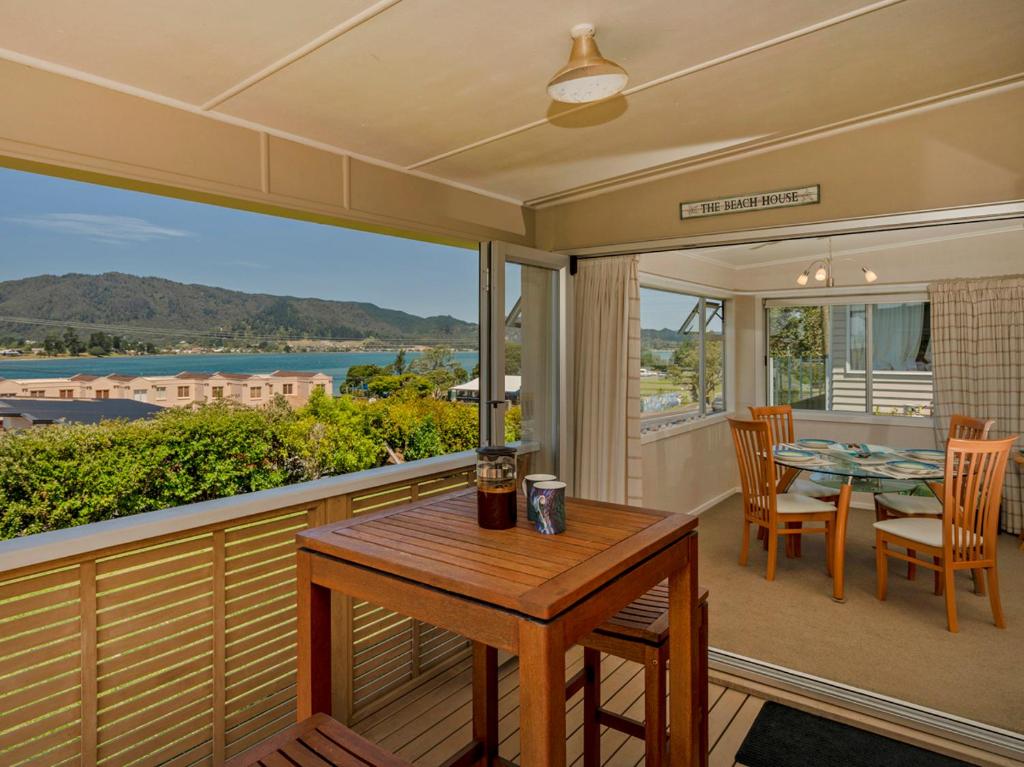 a balcony with a table and chairs and a view of the water at Breakaway - Tairua Bach in Tairua