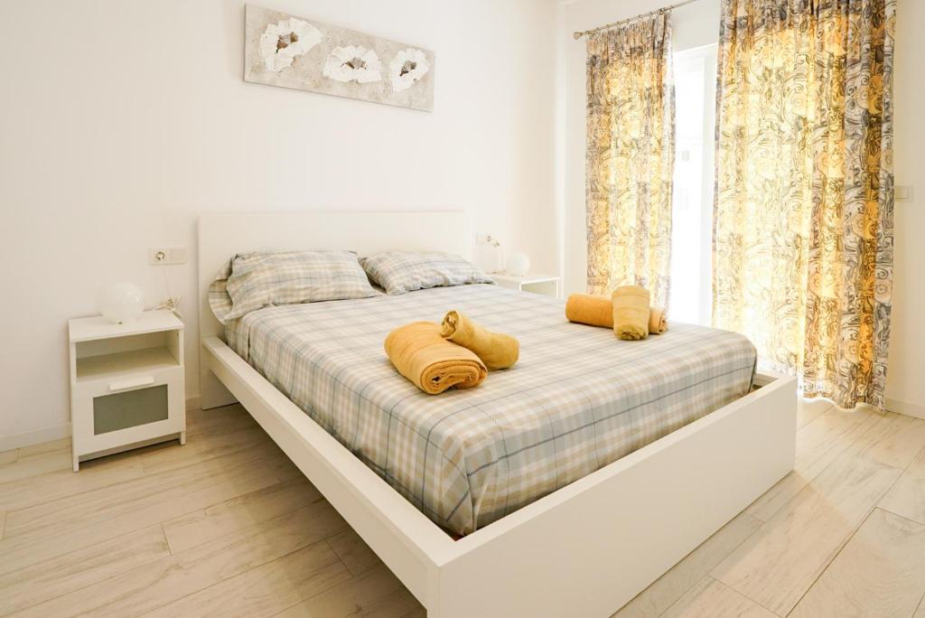 Un dormitorio blanco con una cama grande con almohadas amarillas. en Casa MYA con terreno privado y parking compartido - a 800m de Playa Poniente en Benidorm