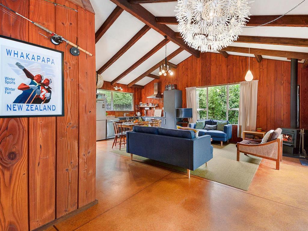 un soggiorno con divano blu e una cucina di Te Kuru Cabin - Pukawa Bay Holiday Home a Kuratau