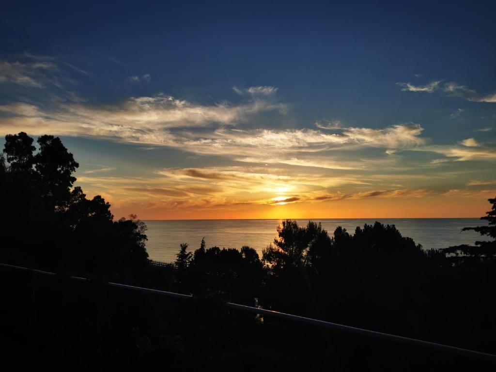 a sunset over the ocean with trees in the foreground at Villetta sul Mare in Acquedolci