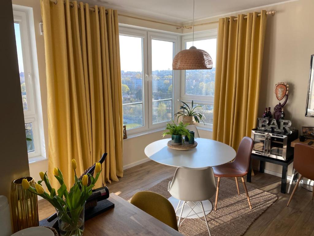 uma sala de estar com cortinas amarelas e uma mesa e cadeiras em Trendy Modern Tower Apartment with Private Parking Space em Gdynia