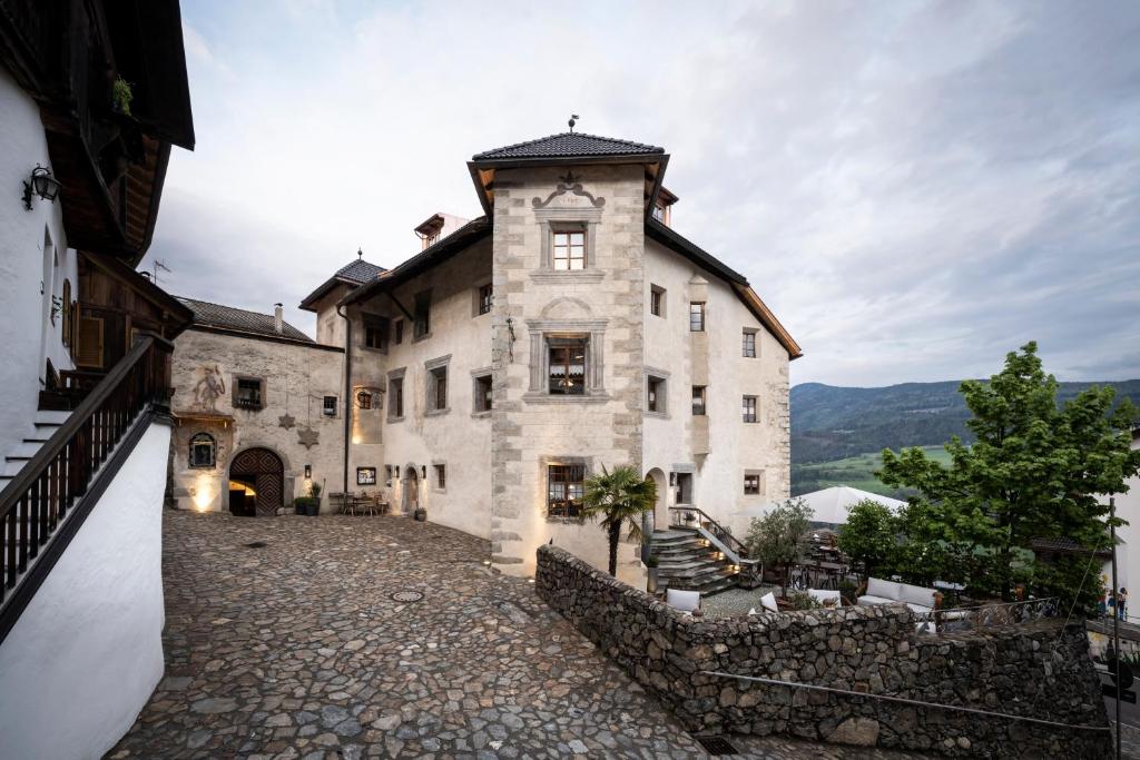 a large stone building with a clock tower at Hotel Ansitz Steinbock in Villandro
