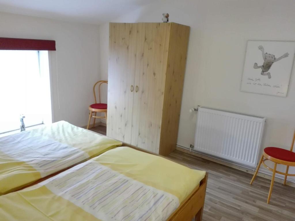 SaalにあるHof Kranichweide, Ferienwohnung "Hrimfaxi"のベッドルーム1室(ベッド1台付)、木製キャビネットが備わります。