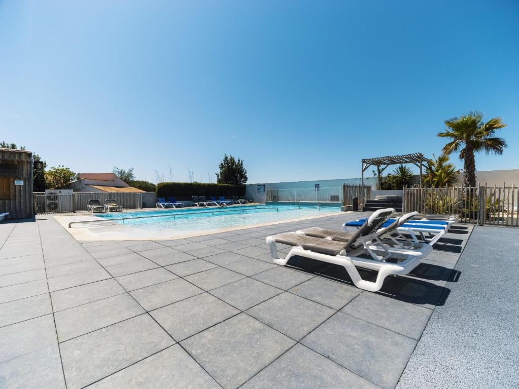 a row of lounge chairs next to a swimming pool at Camping Paradis 4 étoiles Au Port de L'Houmeau - La Rochelle in LʼHoumeau