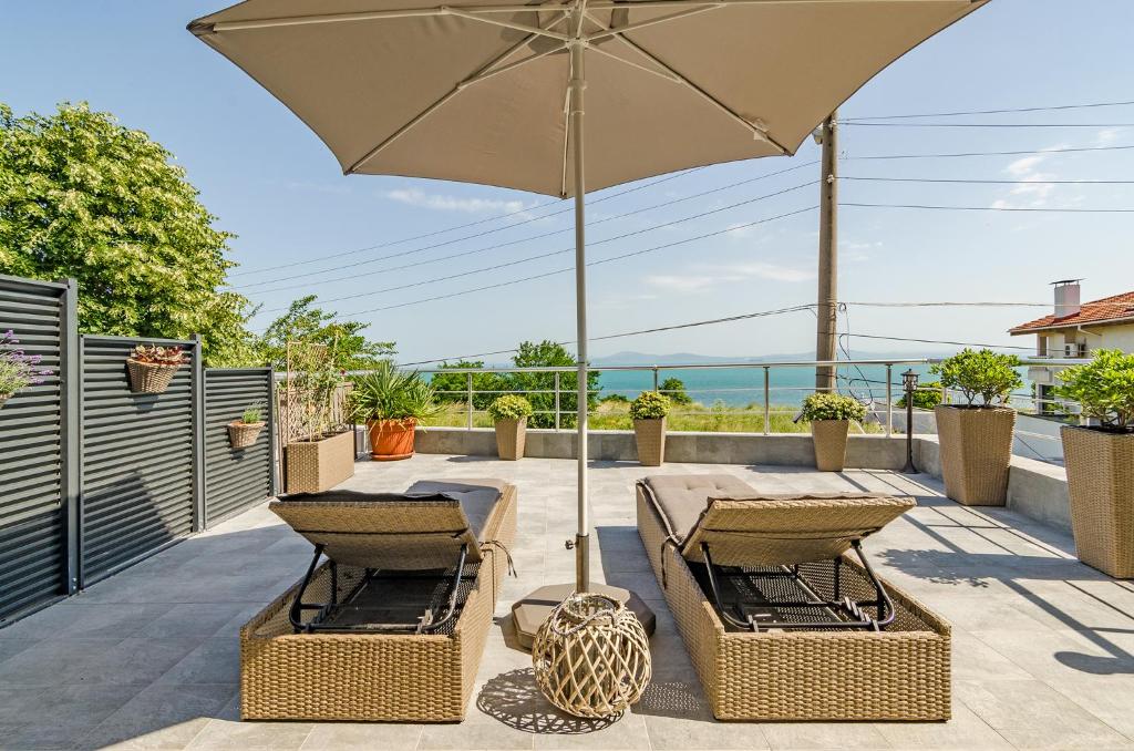 eine Terrasse mit einem Tisch, Stühlen und einem Sonnenschirm in der Unterkunft Апартаменти Ивайло / Ivaylo apartments in Burgas City