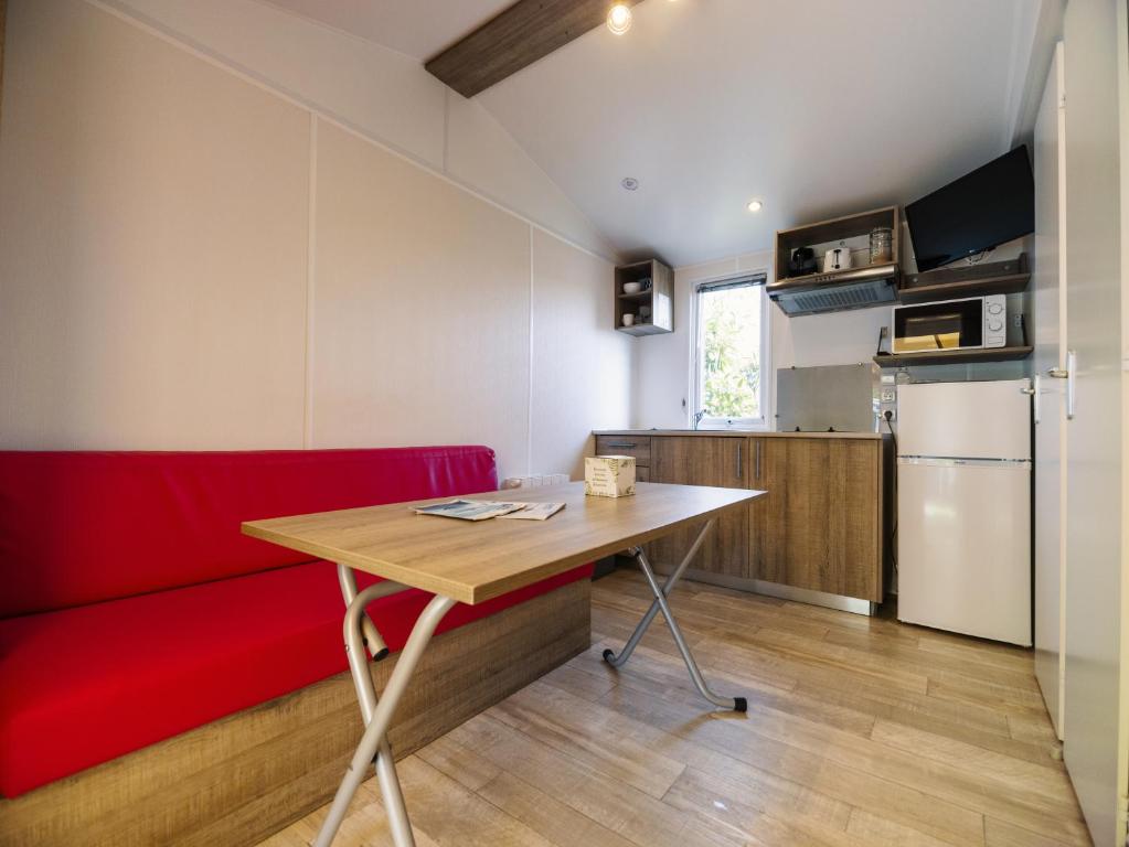 a living room with a red couch and a table at Camping Paradis 4 étoiles Au Port de L'Houmeau - La Rochelle in LʼHoumeau
