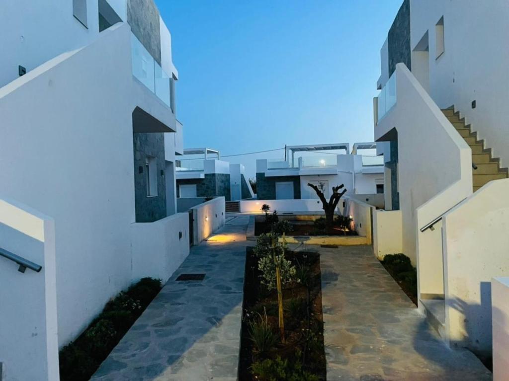 a pathway between two white buildings at night at Gardenhouse 4 in Pilalímata